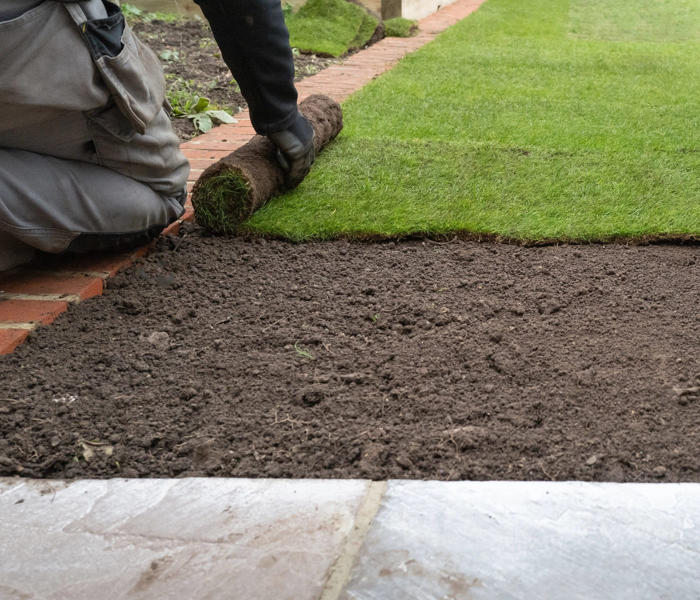 landscaper laying down sod with topsoil