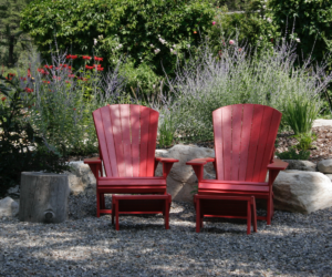 Two red outdoor chairs sitting in rock garden