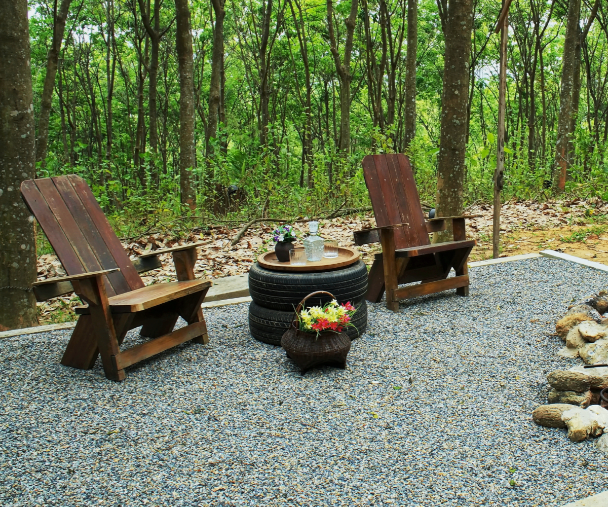 Two rock fire pit with wood table and chairs on gravel floor in the garden