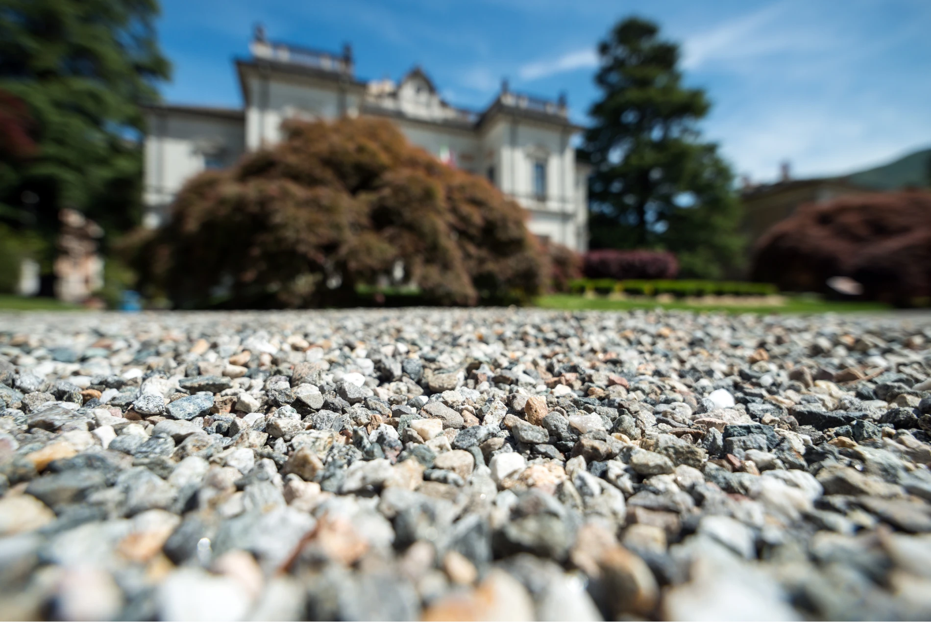 close up of gravel driveway with house in background