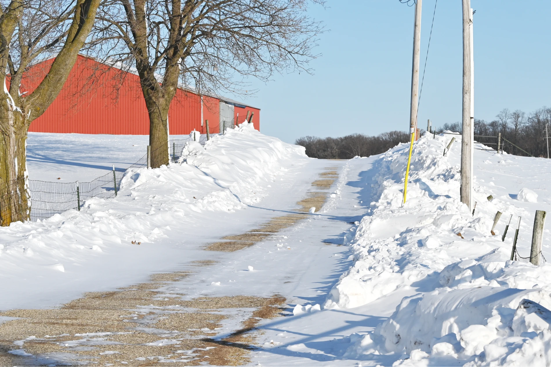 snowy driveway with red barn