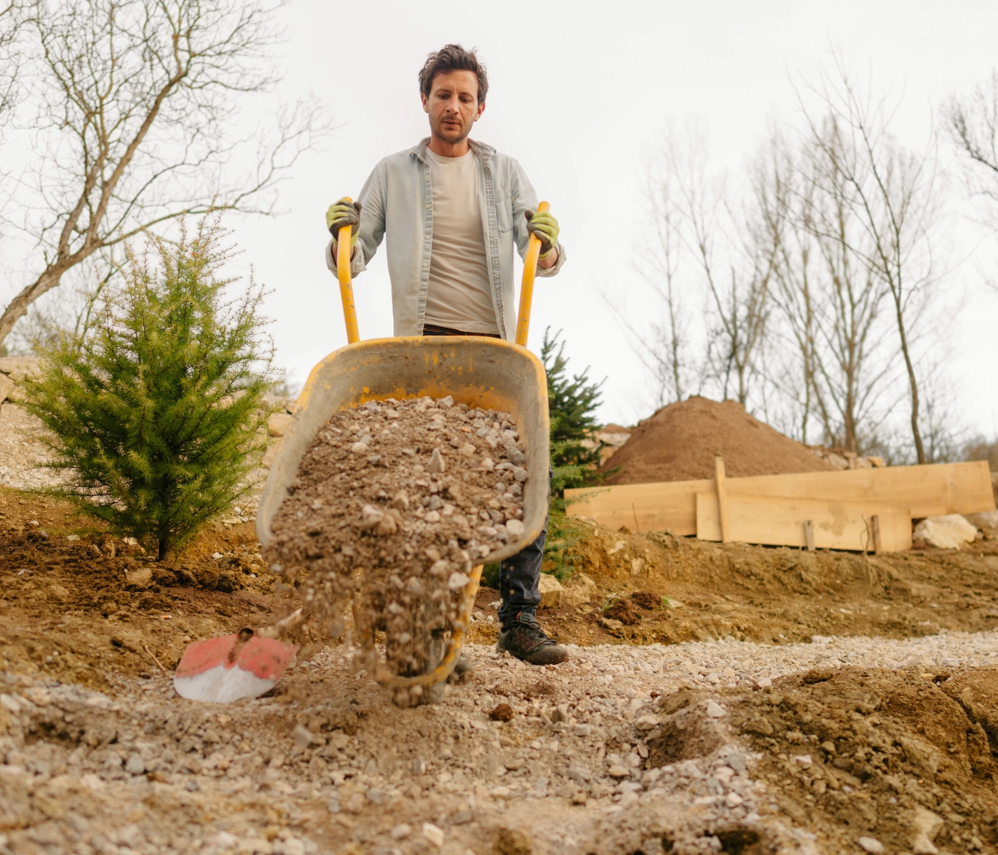 man with wheel barrel dumping dirt and gravel