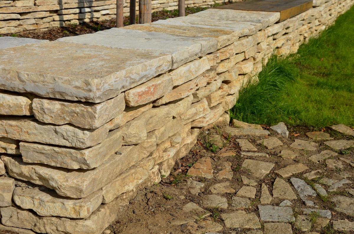 stone marl walls with stone cladding by the pool, ponds, fire tanks. metal bike racks and trash cans included in the wall. rusty corten steel railing, beige lime pavement