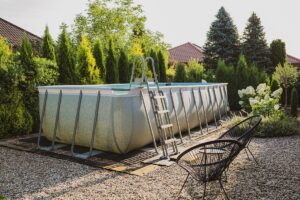 Above ground, rack swimming pool in the pebble (gravel) garden. Summer holiday recreation.