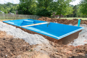 Gravel is poured around fiberglass swimming pool to stabilize it with mortar sand